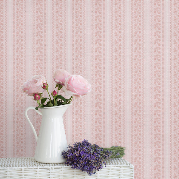 Blush pink floral stripe wallpaper with dusty rose botanical vines, wavy vertical borders, and a soft textured background for nursery or bedroom decor.