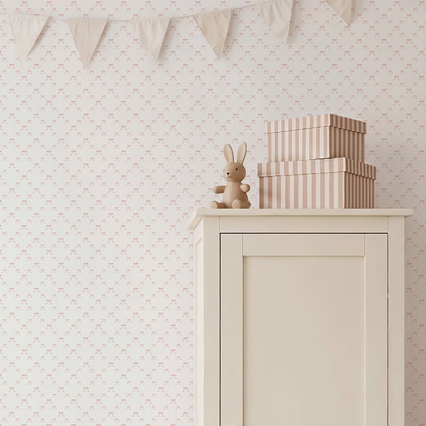 Watercolor pink ribbon wallpaper with a repeating bow pattern, creating a light coquette style for a nursery, playroom, or girls bedroom.