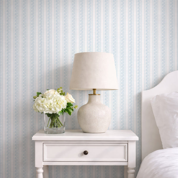 Light blue floral stripe wallpaper with hand drawn botanical stems, wavy border details, and soft linen texture for coastal cottage nursery decor.