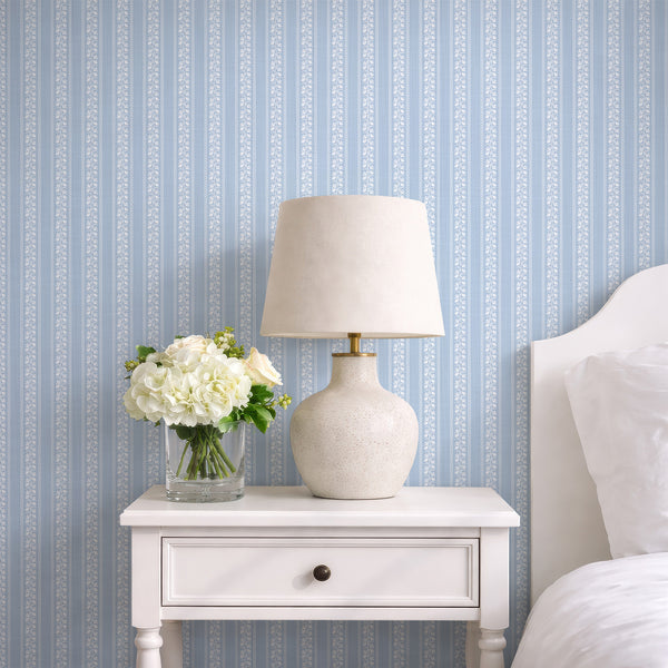 Light blue floral stripe wallpaper with white botanical line art, vertical vine pattern, and soft cottagecore style for nursery or bedroom decor.