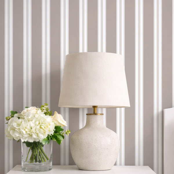 Taupe pinstripe wallpaper with wide neutral bands and slim white line details, designed for an elegant bedroom, dining room, or office accent wall.