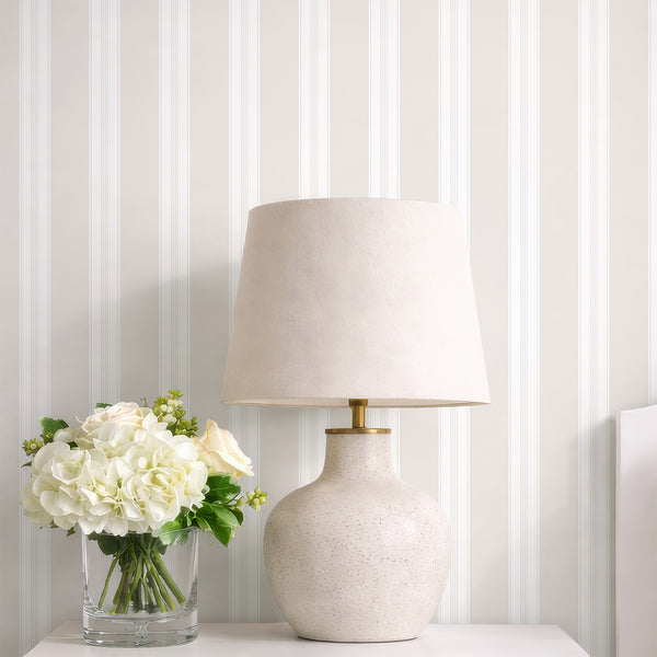 Soft beige pinstripe wallpaper with wide vertical panels and delicate line details, creating a subtle neutral backdrop for bedroom or living room decor.