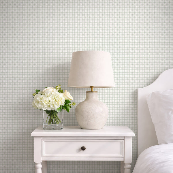 Modern geometric wallpaper featuring muted sage green interlocking shapes on a warm white background for a bedroom, office or living room.