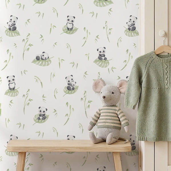 Watercolor panda nursery wallpaper featuring a cute black and white panda sitting on a soft green tropical leaf with delicate bamboo branches.