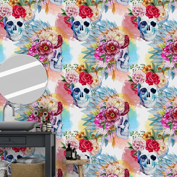 Artistic floral skulls wallpaper for an accent wall featuring watercolor skulls with magenta, rose, and coral floral crowns on pastel washes. Perfect for adding a gothic yet colorful touch to a bedroom or boutique.